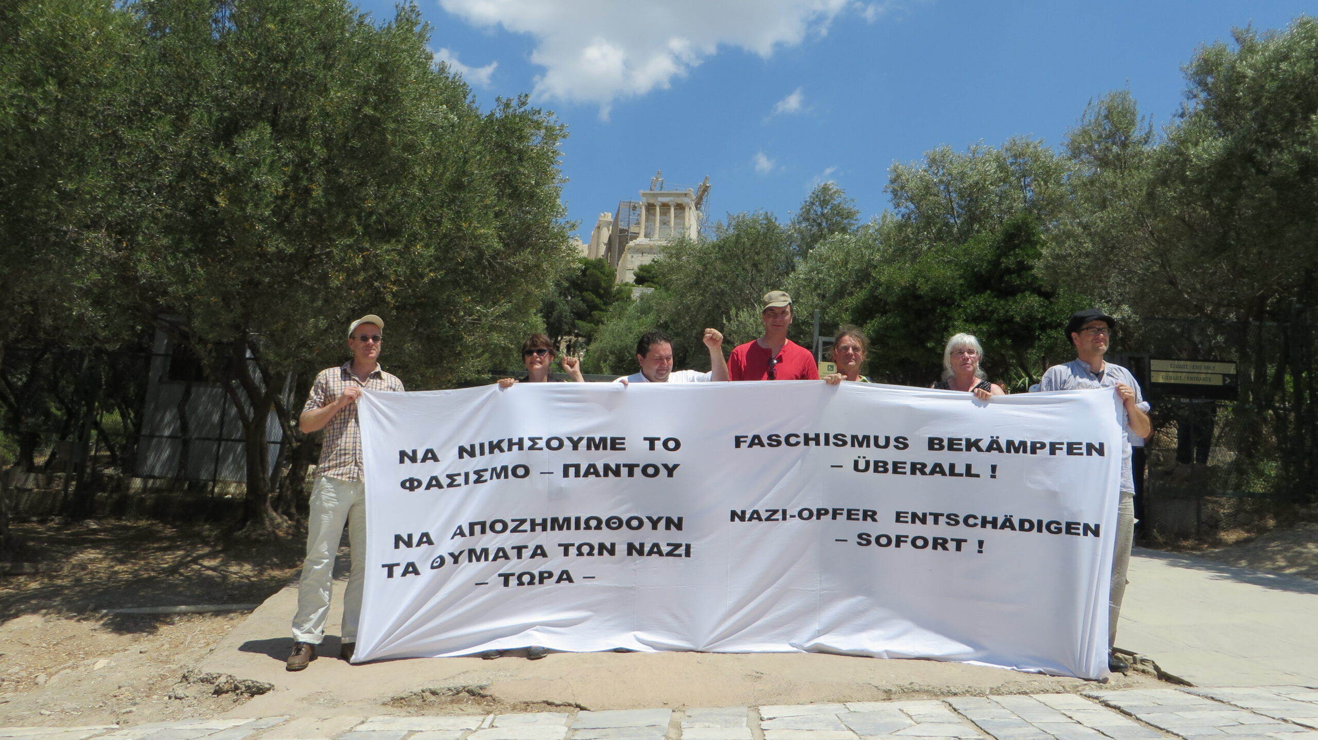 Ak Distomo vor der Akropolis mit einem Transparent "Faschismus bekämpfen - überall! Nazi-Opfer Entschädigen -sofort!"